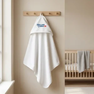 Witte badhanddoek met Holland Casino logo aan houten kapstok in beige babykamer