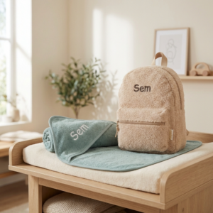 Beige teddy rugzak met naam Sem en mintgroene handdoek op houten commode in babykamer