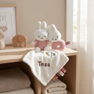 Babykamer met houten plank, Nijntje knuffels in roze, rammelaar en wit knuffeldoekje met naam Tess geborduurd