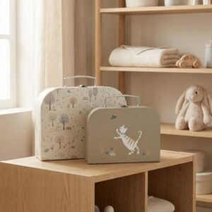 Kinderkoffers met dierenprint op houten tafel in neutrale babykamer met opbergkast en knuffels