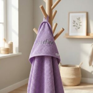 Paarse handdoek met geborduurd naam Josefien hangend aan houten kapstok in Scandinavische badkamer