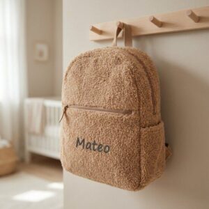 Beige teddy rugzak met naam Mateo geborduurd, hangend aan houten kapstok in kinderkamer